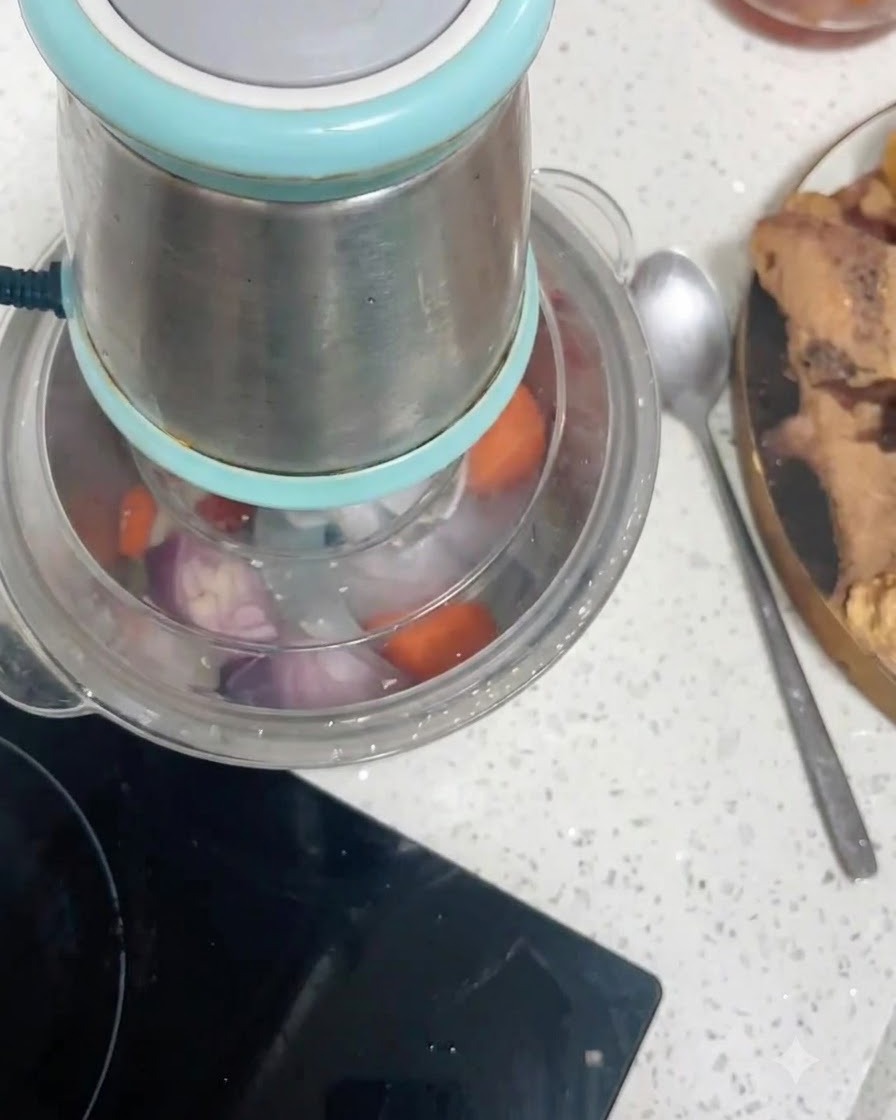 Karottenstücke und rote Zwiebelstücke in einem Küchenmaschinenbehälter werden zerkleinert.