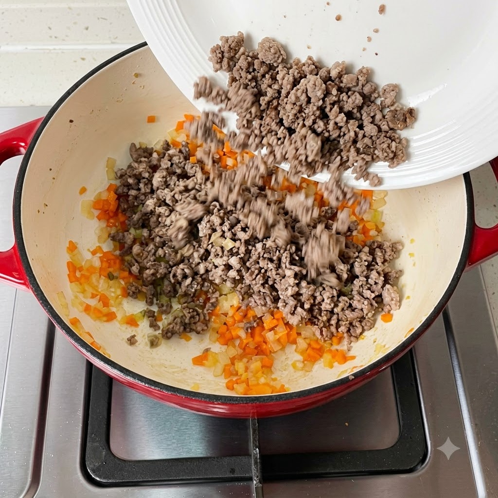 Gegartes Hackfleisch wird zurück in die Pfanne mit dem Gemüse gegeben.