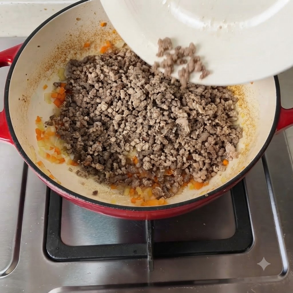 Verschiedene Gewürze und gehackte Tomaten werden zur Fleisch-Gemüse-Mischung gegeben.