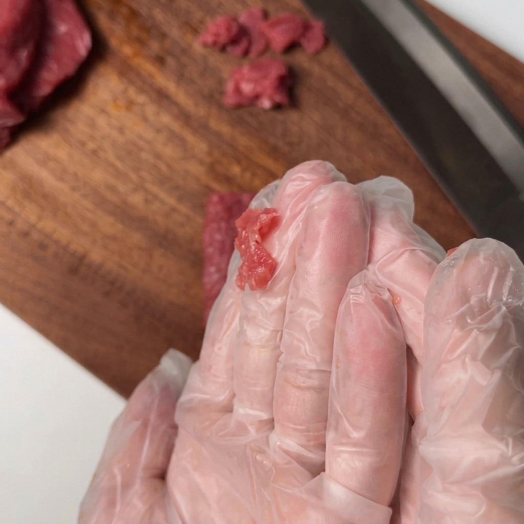 Geschnittenes Rinderfilet wird in einer Schüssel mit Gewürzen vermengt.