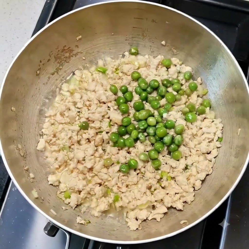 Grüne Erbsen gleichmäßig mit Hähnchen und Gewürzen in einer Kochpfanne vermischt.