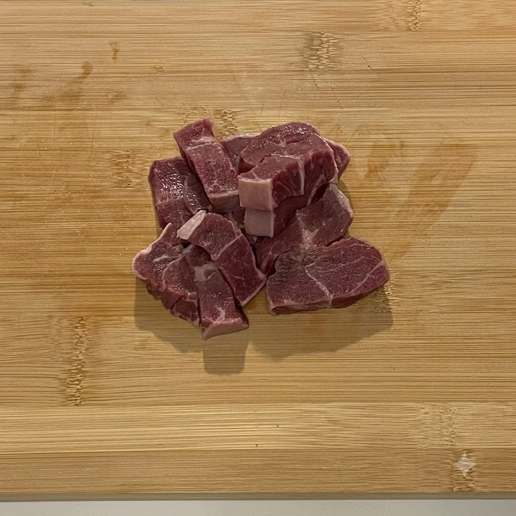 Stücke von rohem Rindfleisch in einer Edelstahl-Küchenmaschine.
