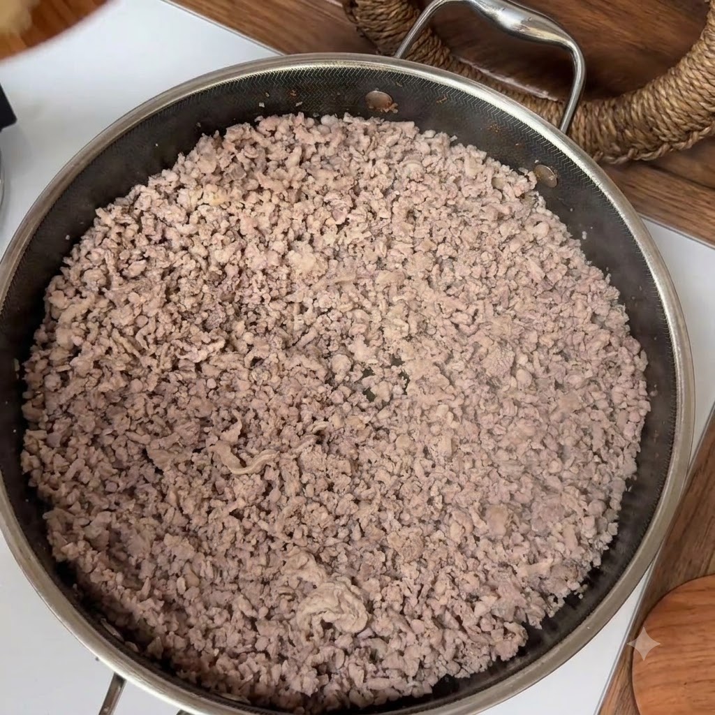 Gebratenes Hackfleisch in einer Edelstahlpfanne während des Kochvorgangs.
