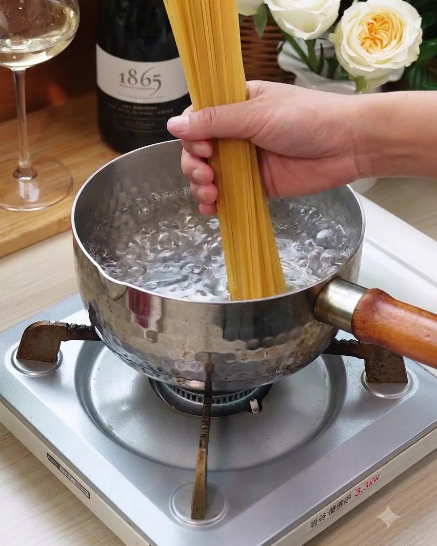 Ein Bündel trockene Spaghetti wird in einen Topf mit kochendem Wasser auf dem Herd gegeben.