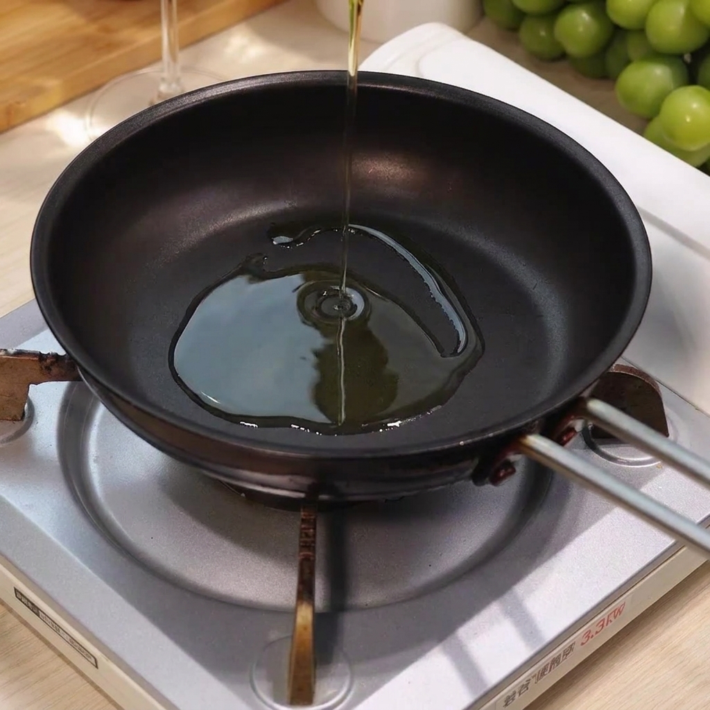 Olivenöl wird in die Mitte einer heißen, leeren Bratpfanne auf einer Herdplatte gegossen.