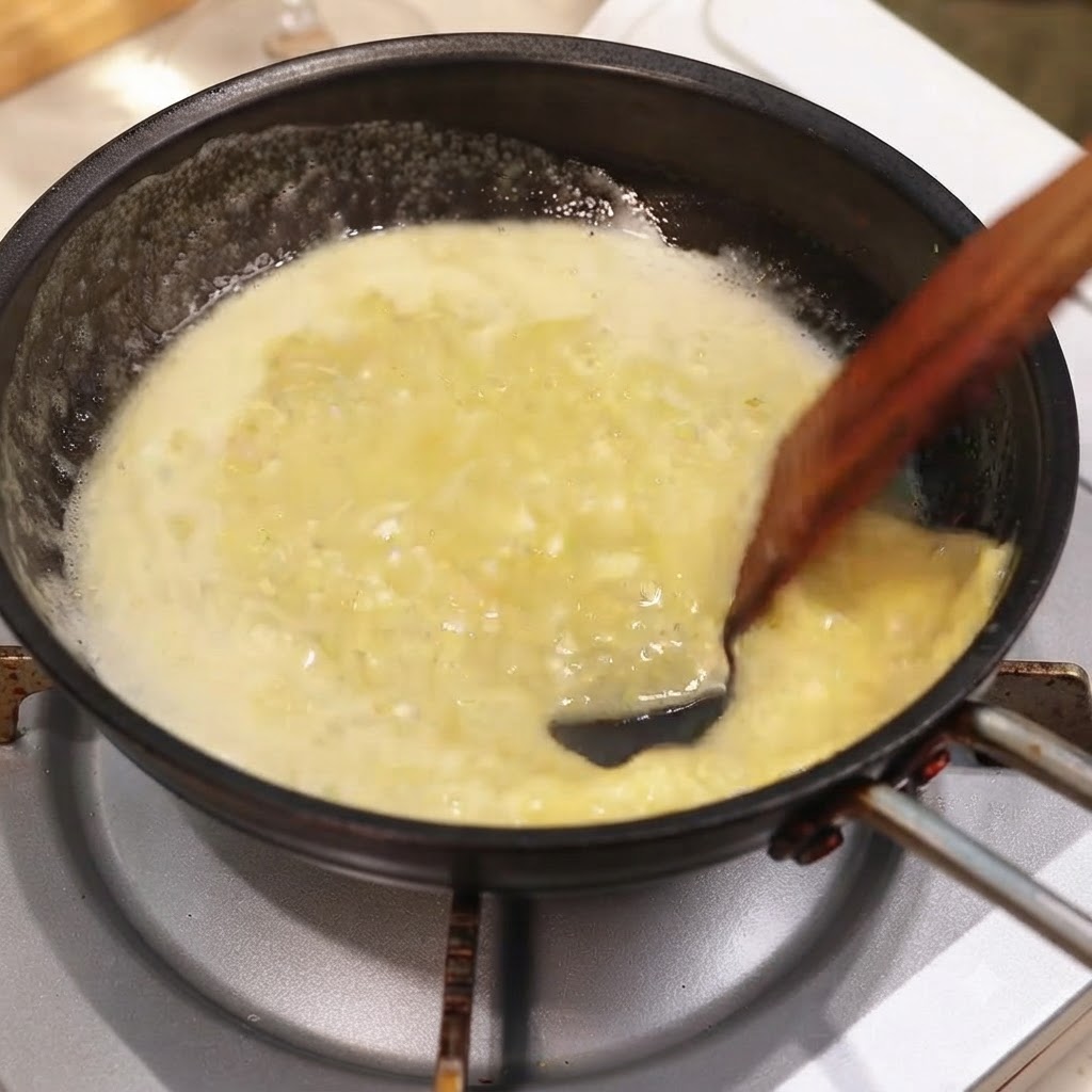 Eine Pfanne mit reichhaltiger Knoblauch-Zitronen-Buttersauce wird mit Kräutern und einem Holzlöffel vermischt.