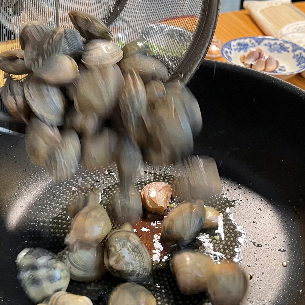 Muscheln werden aus einem Metallsieb in eine Pfanne mit Knoblauch gegeben.