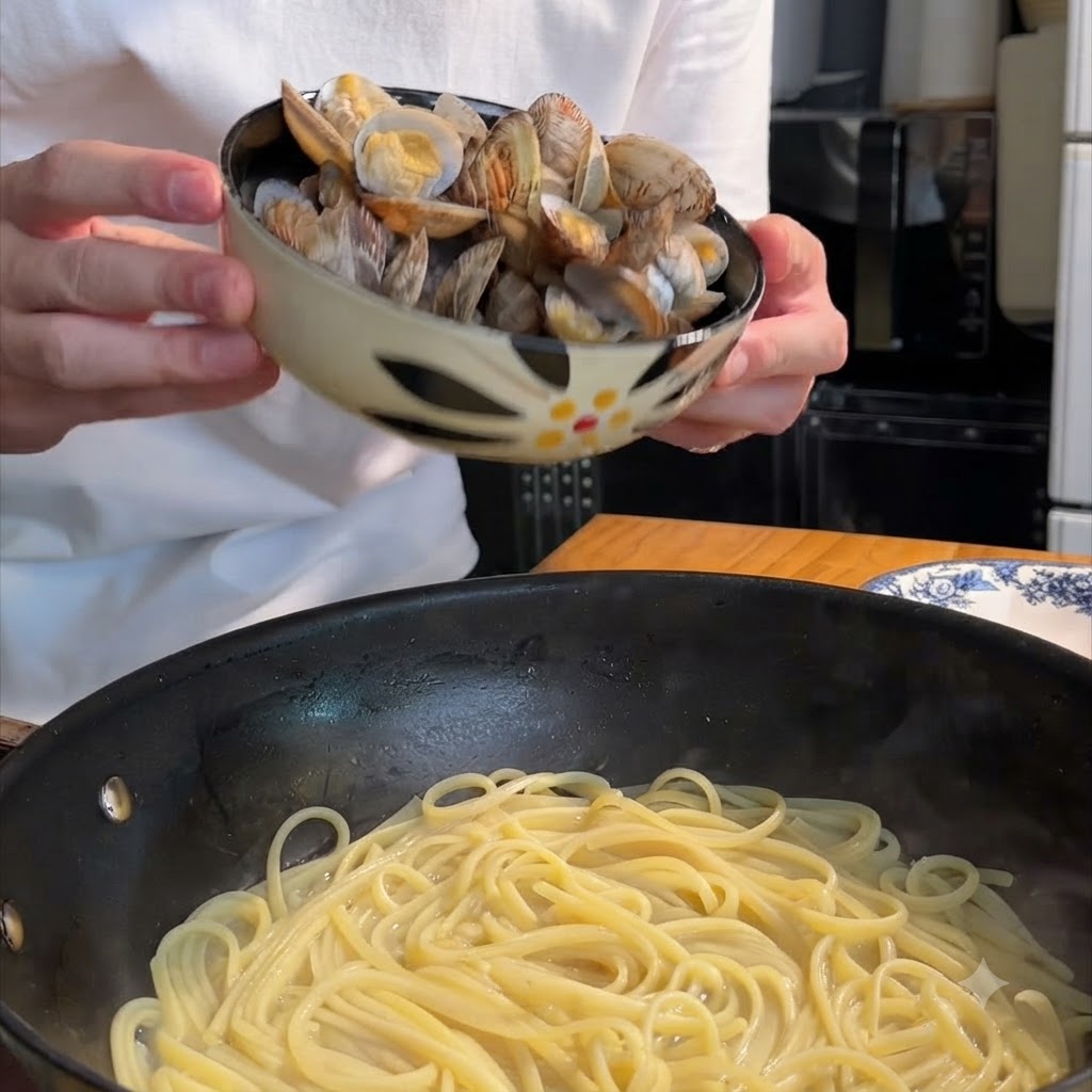 Gekochte Muscheln werden in eine mit Spaghetti gefüllte Bratpfanne gegeben.
