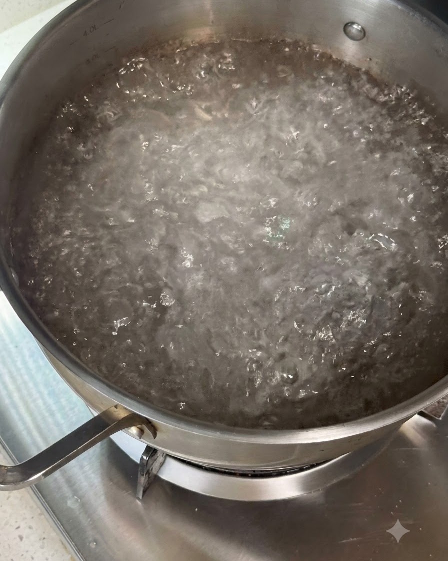 Trockene Pasta wird mit Kochutensilien in einen Topf mit kochendem Wasser gerührt.