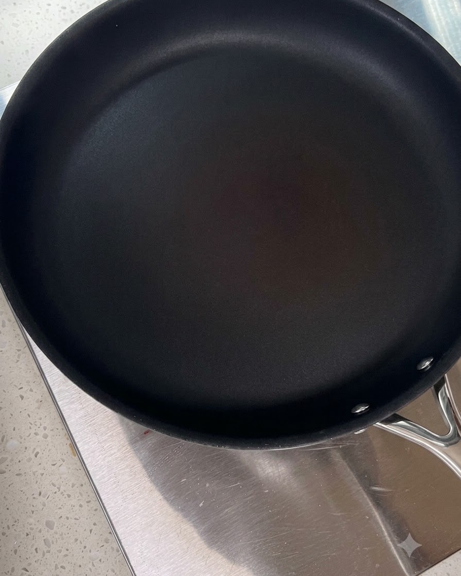 Eine saubere schwarze Bratpfanne erhitzt sich auf einer Herdplatte.
