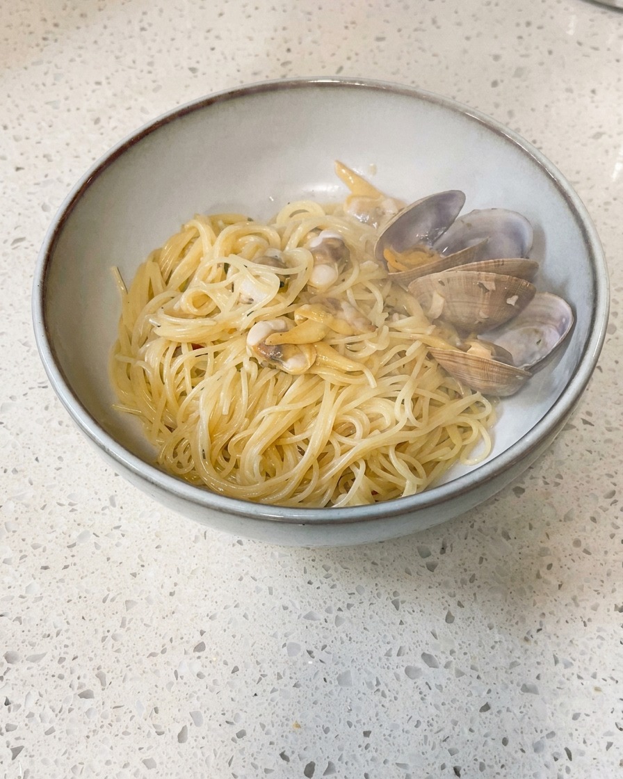 Kleine Stücke kalter Butter werden in eine Pfanne mit gekochten Muscheln und Brühe gegeben.