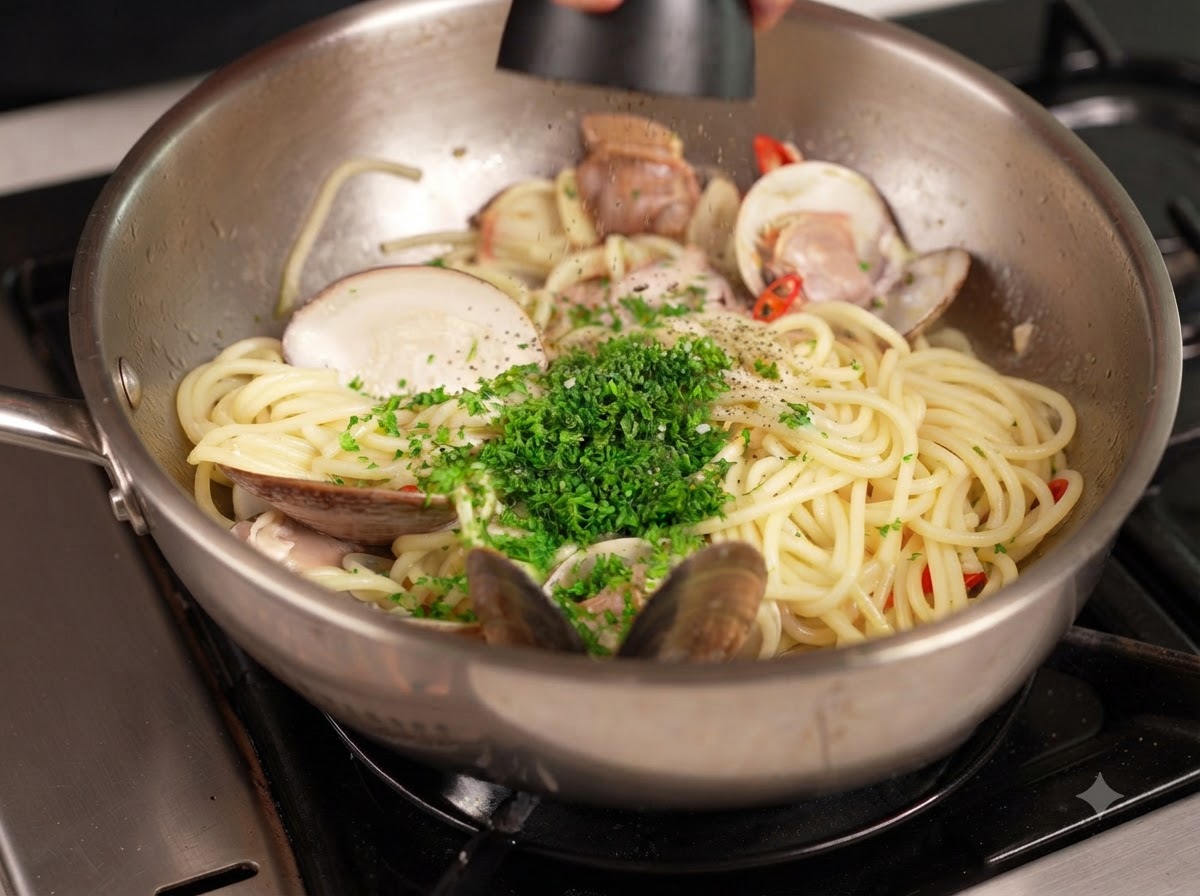 Schwarzer Pfeffer wird aus einer Mühle über eine Pfanne mit Pasta und Muscheln gemahlen, die mit gehackter grüner Petersilie garniert ist.