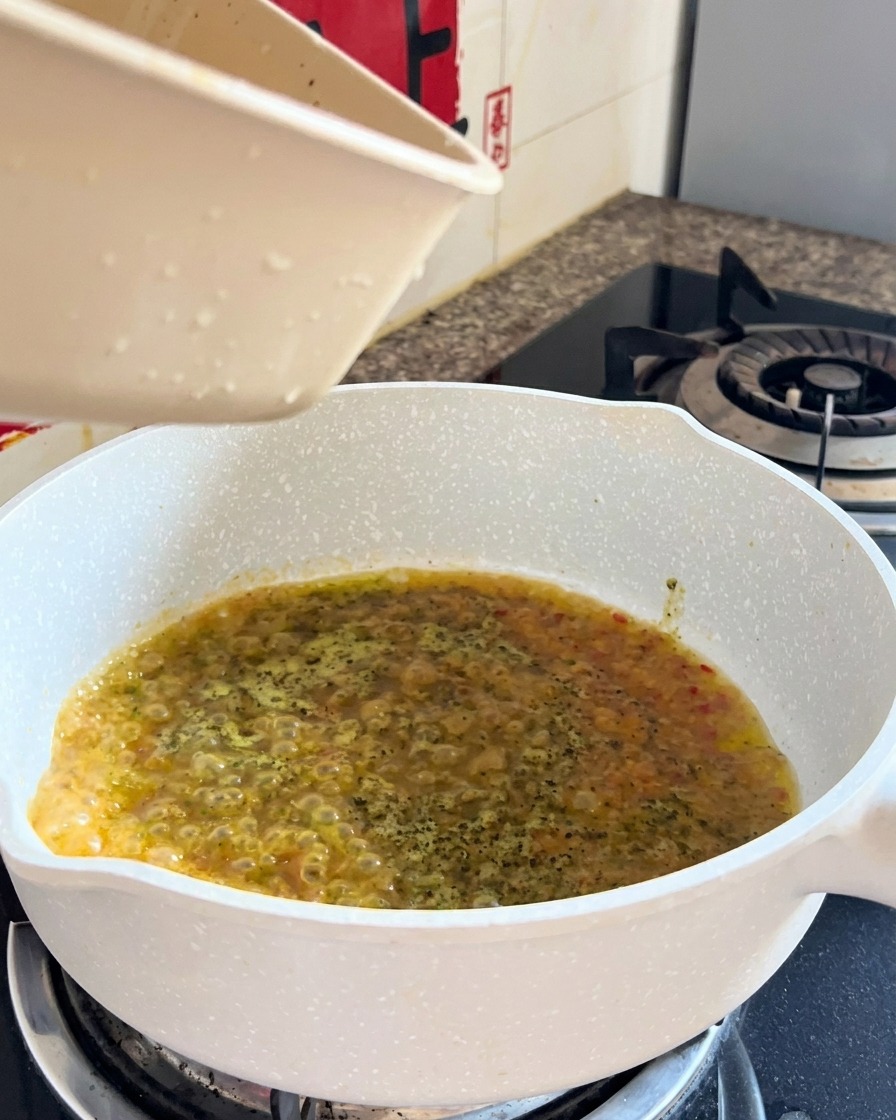 Gekochte Spaghetti und Flüssigkeit werden beim finalen Schwenken in einer Pfanne kombiniert.