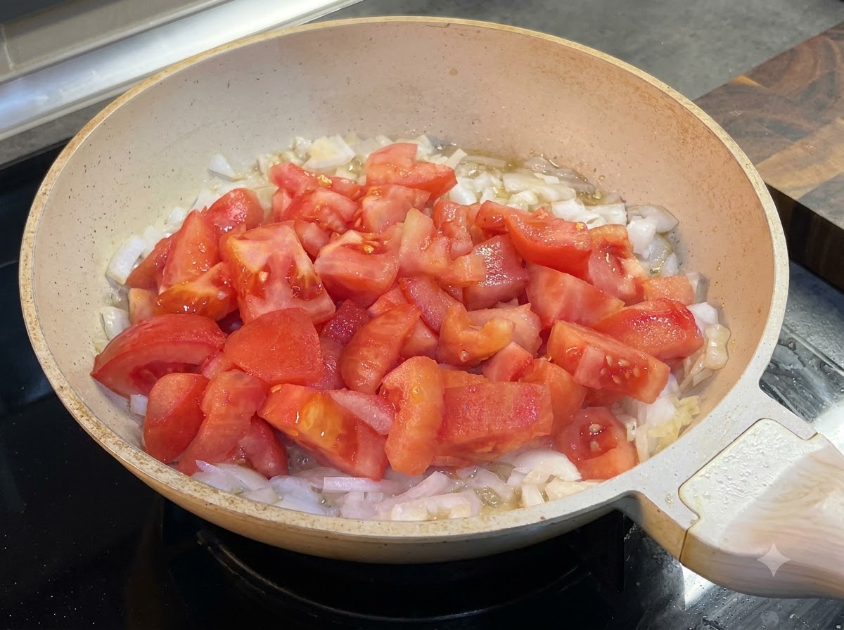 Ketchup wird zu den Tomaten und Zwiebeln in die Pfanne gegeben.