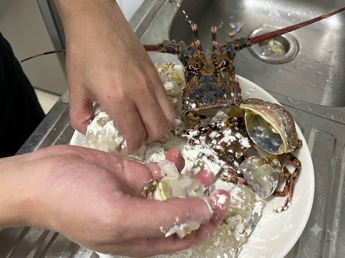 Hände wenden auf einem Teller aktiv rohe Langustenfleisch- und Panzerstücke in weißer Speisestärke, um eine gleichmäßige Schicht zu gewährleisten.