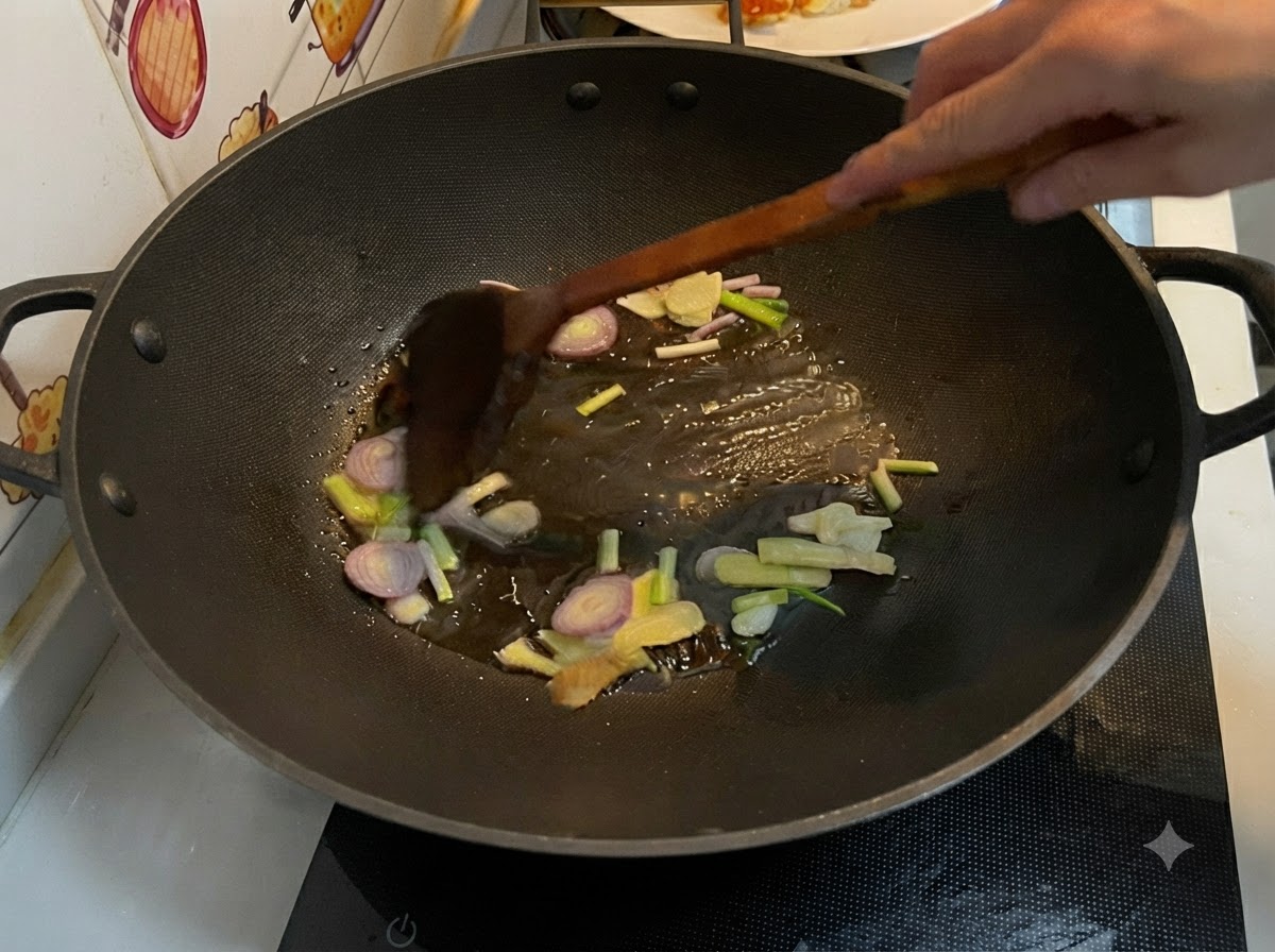 Geschnittener Ingwer, Knoblauch, Schalotten und Frühlingszwiebeln braten in heißem Öl in einem Wok und werden mit einem Holzspatel umgerührt.