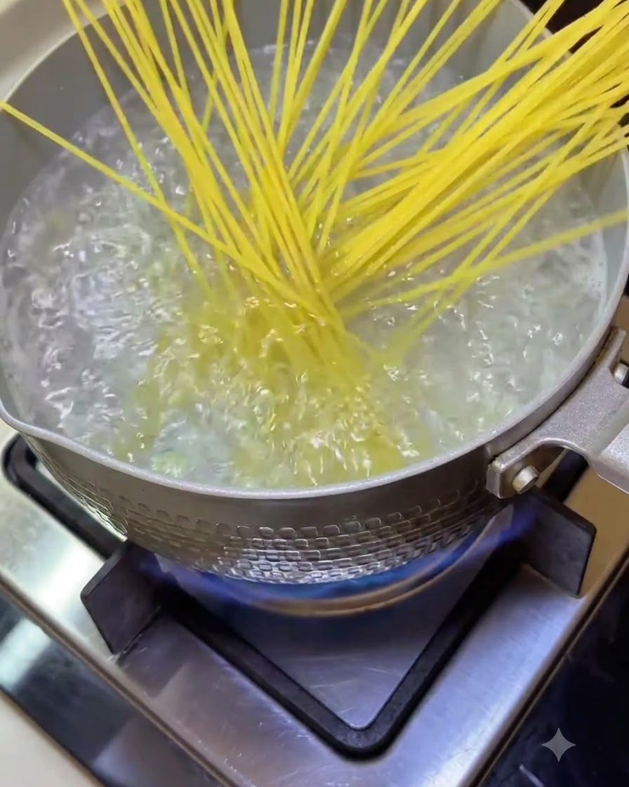 Spaghetti-Nudeln werden in einen Topf mit sprudelnd kochendem Wasser auf dem Herd gegeben.