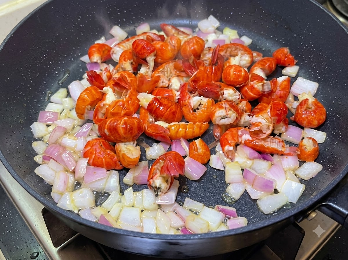 Krebsschwänze und gewürfelte Zwiebeln werden zusammen in einer Pfanne gekocht.
