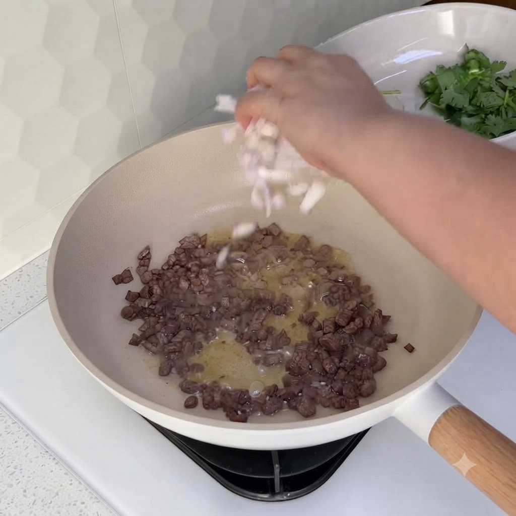 Gewürfelte Zwiebeln werden in einen Wok mit bereits angebratenem Rinderhackfleisch gestreut.