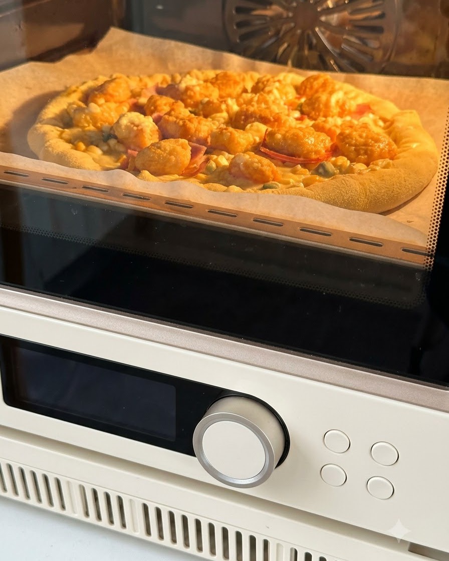 Eine fertig belegte Pizza auf Backpapier wird in einen warm orange leuchtenden Ofen geschoben.