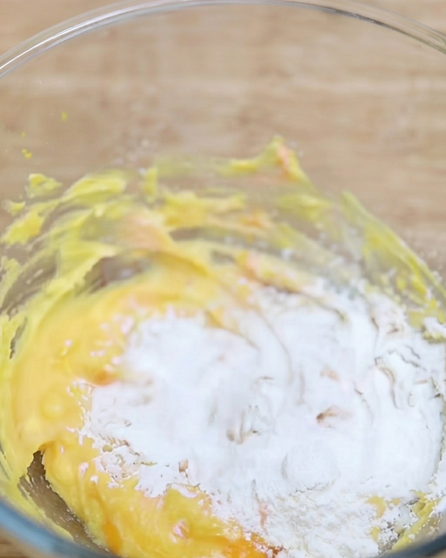 Matchapulver wird in eine Schüssel mit der gelben Teigbasis gesiebt.