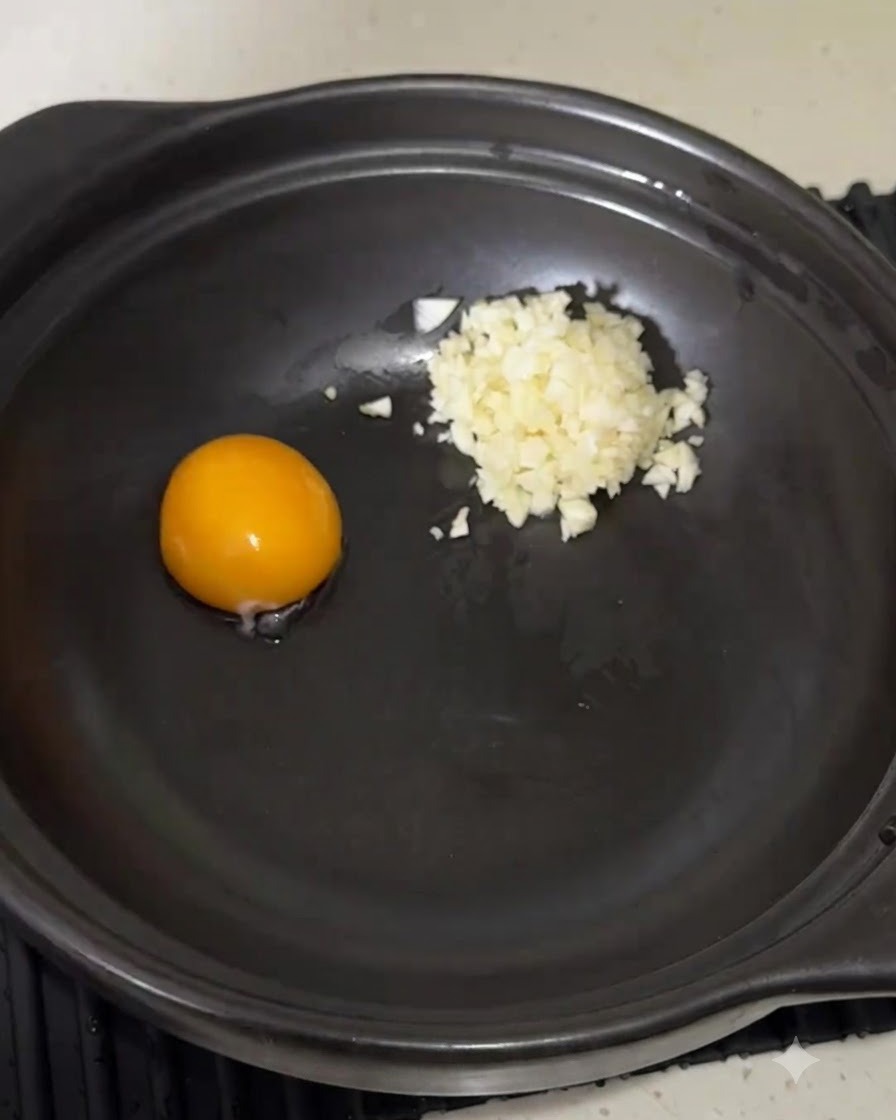 Instant-Nudel-Würzungspulver wird neben dem Eigelb und Knoblauch in den Topf geschüttet.
