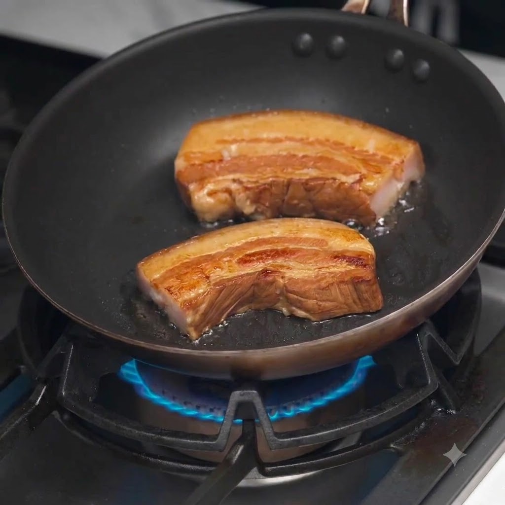 Dicke Scheiben geschmorter Schweinebauch braten und bräunen in einer heißen schwarzen Pfanne.