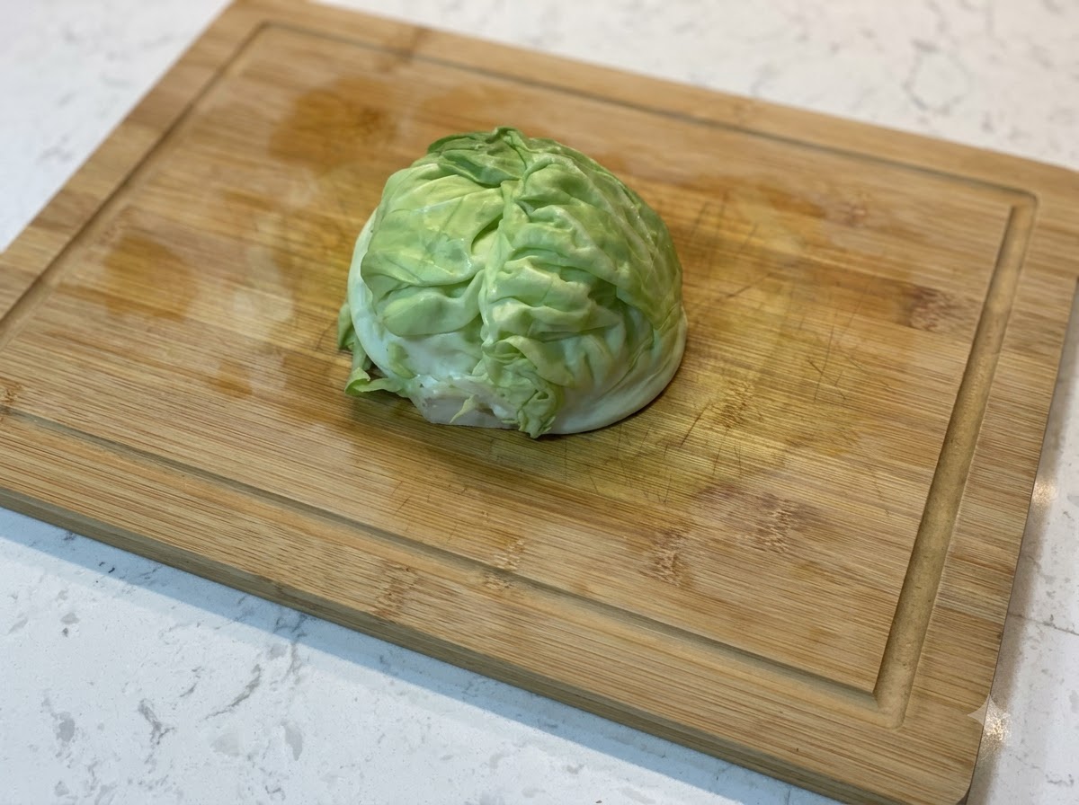 Ein Keil frischer grüner Kohl auf einem Holzschneidebrett.