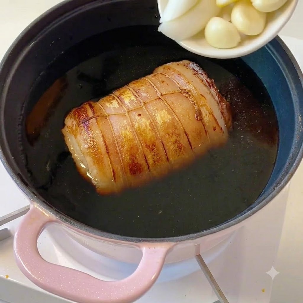 Eine kleine weiße Schale mit geschnittenen Frühlingszwiebeln, Ingwerstücken und Knoblauchzehen wird in den Topf entleert.