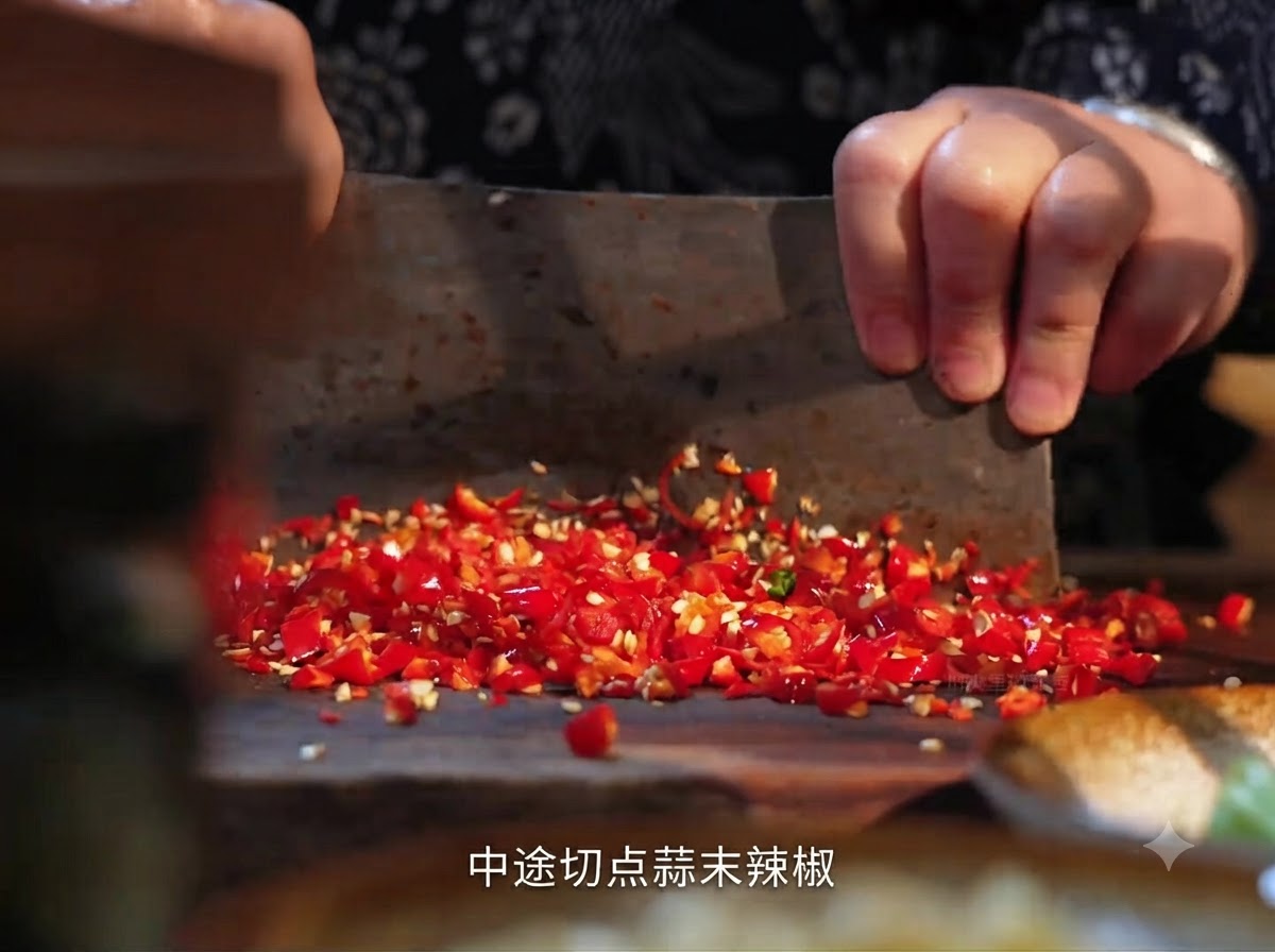 Frische rote Chilis werden mit einem Hackbeil auf einem Holzbrett gehackt.