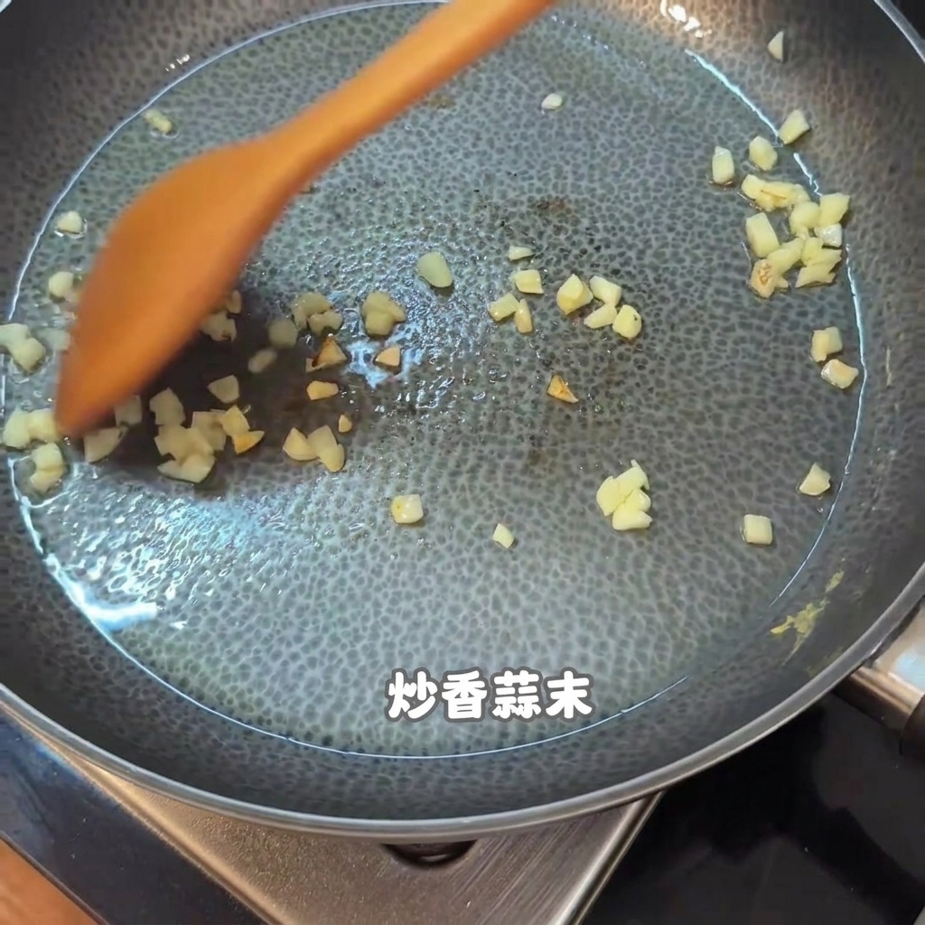 Gehackter Knoblauch und Essensreste werden mit einem orangefarbenen Holzspatel in einer Antihaft-Pfanne umgerührt.