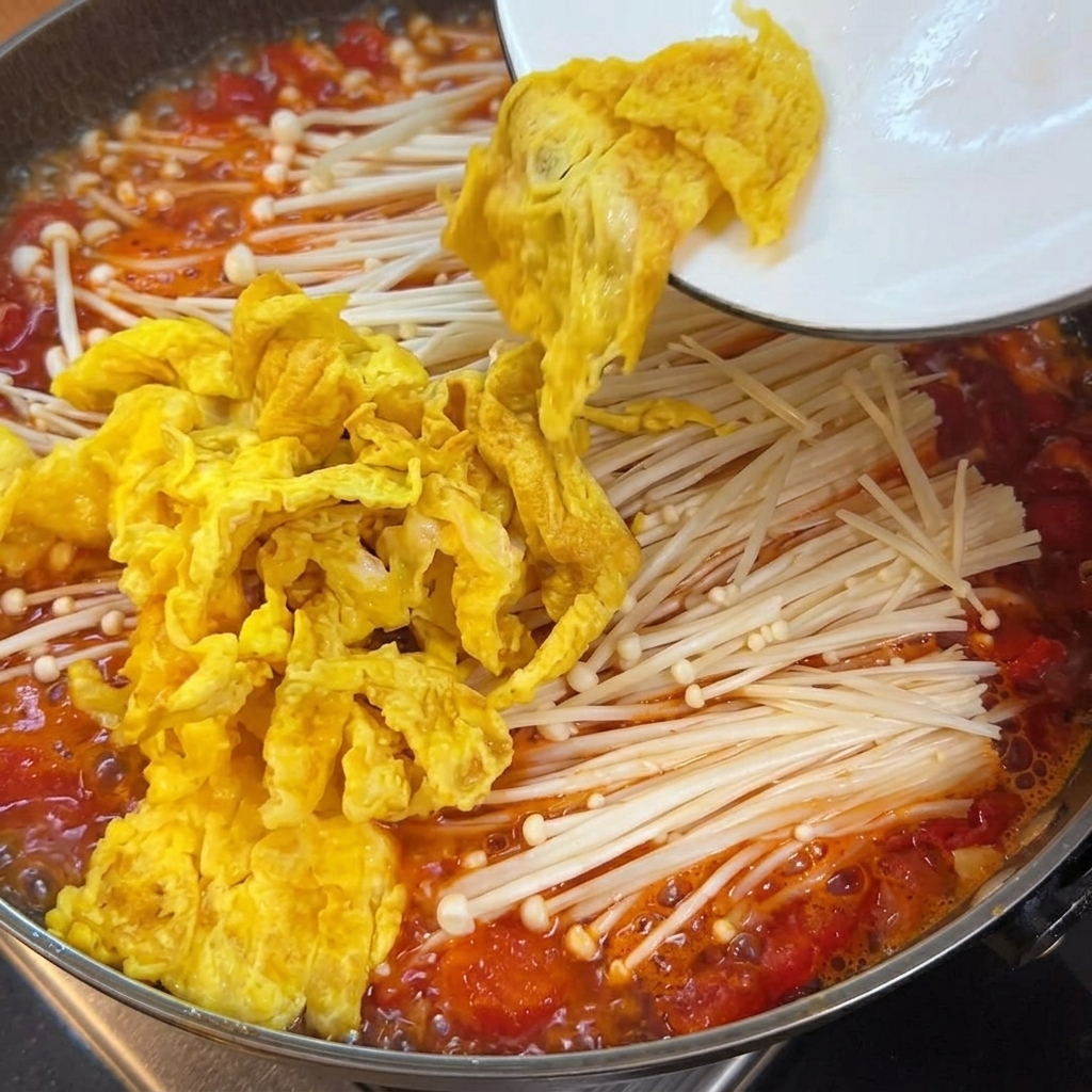 Zarte Tofuwürfel werden in den Topf mit Tomatenbrühe, Pilzen und Eiern gegeben.