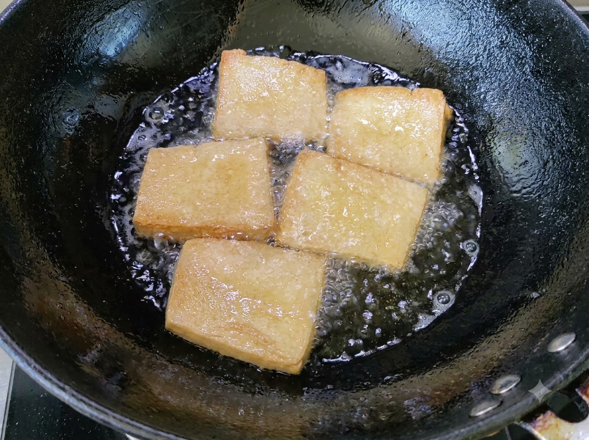 Goldbraune Tofustücke braten in einem Wok mit blubberndem Öl.