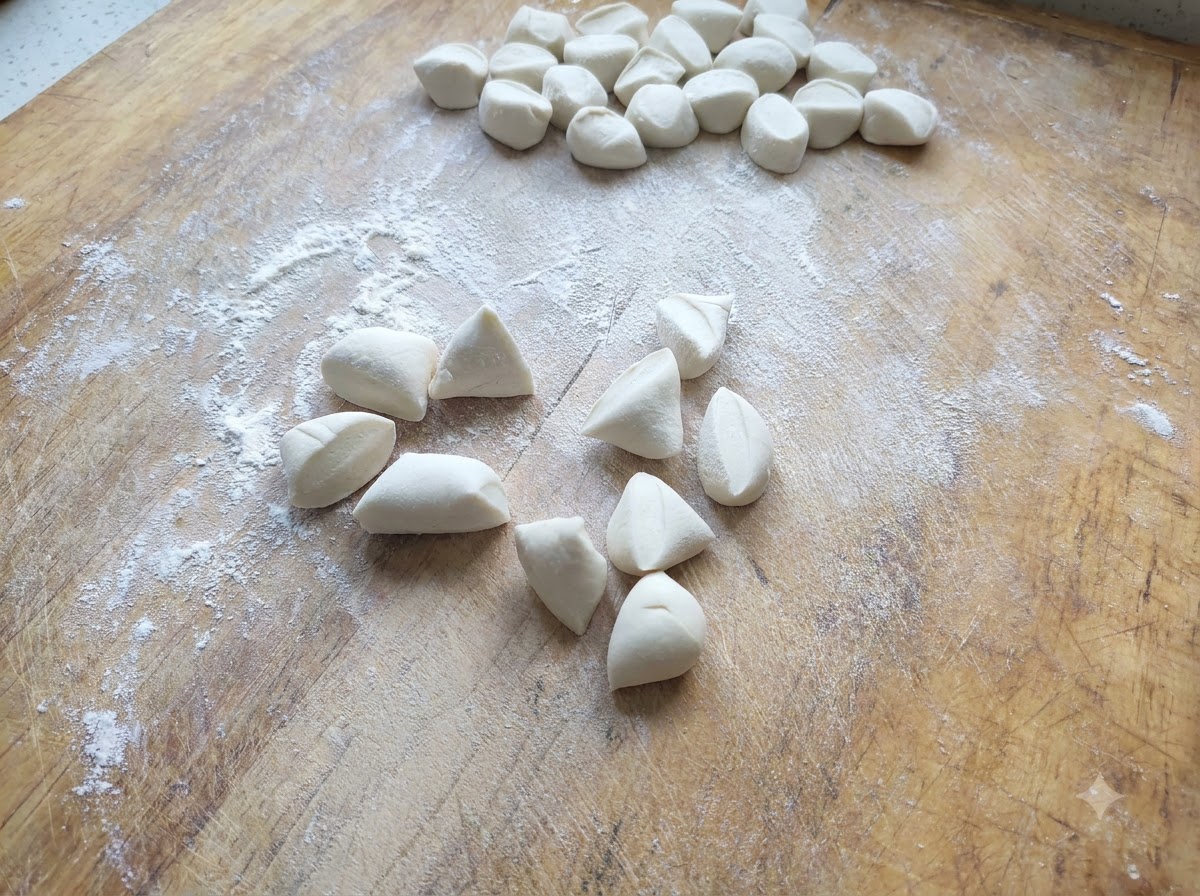 Kleine Stücke weißer Teigtaschenteig geschnitten und auf einem bemehlten Holzbrett verteilt.