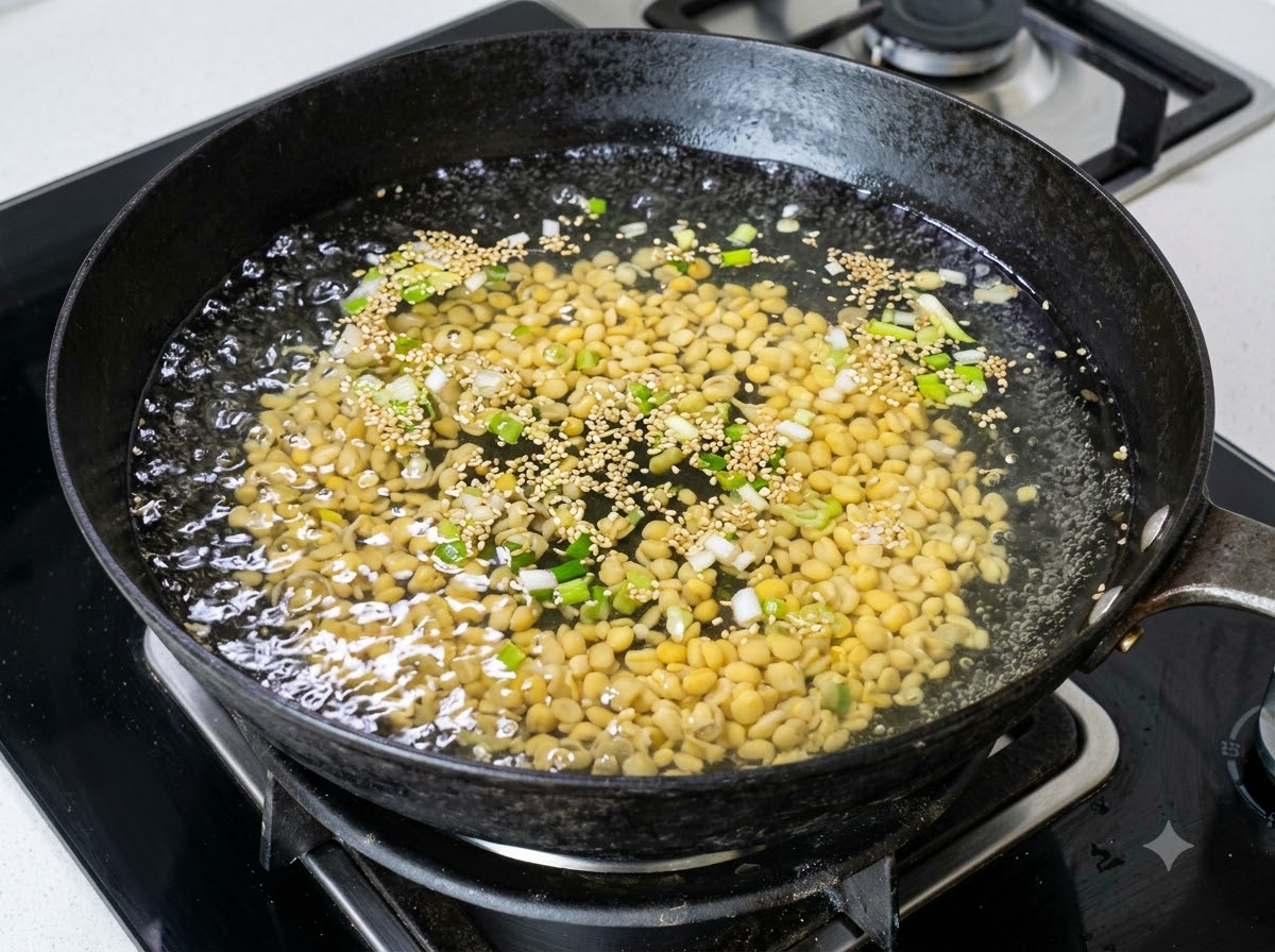 Eine große Menge gelber Sojasprossen kocht in einem Wok mit Wasser und gehackten Frühlingszwiebeln.