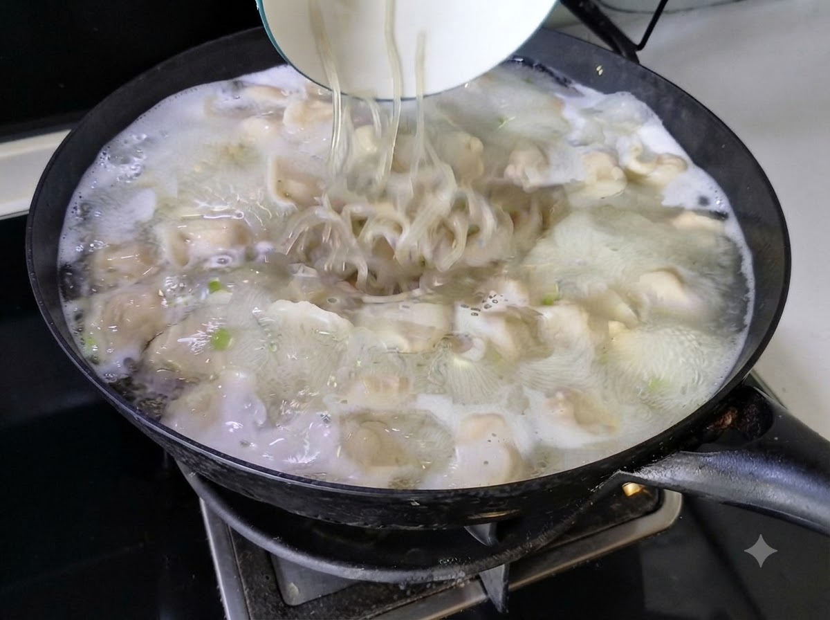 Nudeln werden aus einer weißen Schüssel in die blubbernde Teigtaschensuppe in einem Wok geschüttet.