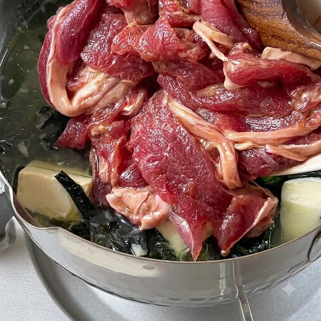Marinierte Rindfleischstreifen werden bei schwacher Hitze in einen Topf mit köchelnder Suppe gegeben.