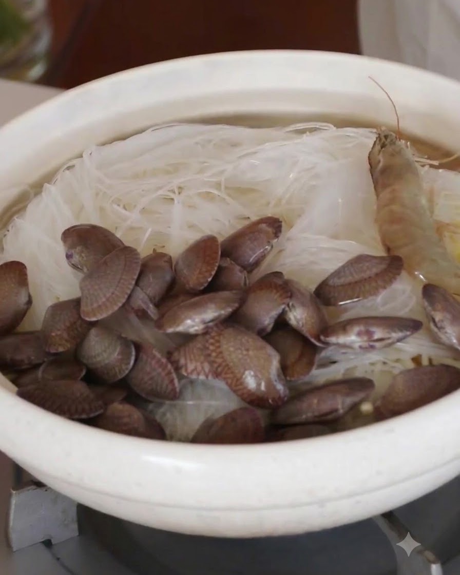 Ganze rohe Garnelen und frische Muscheln sind in einem Kreis über den Glasnudeln angeordnet.