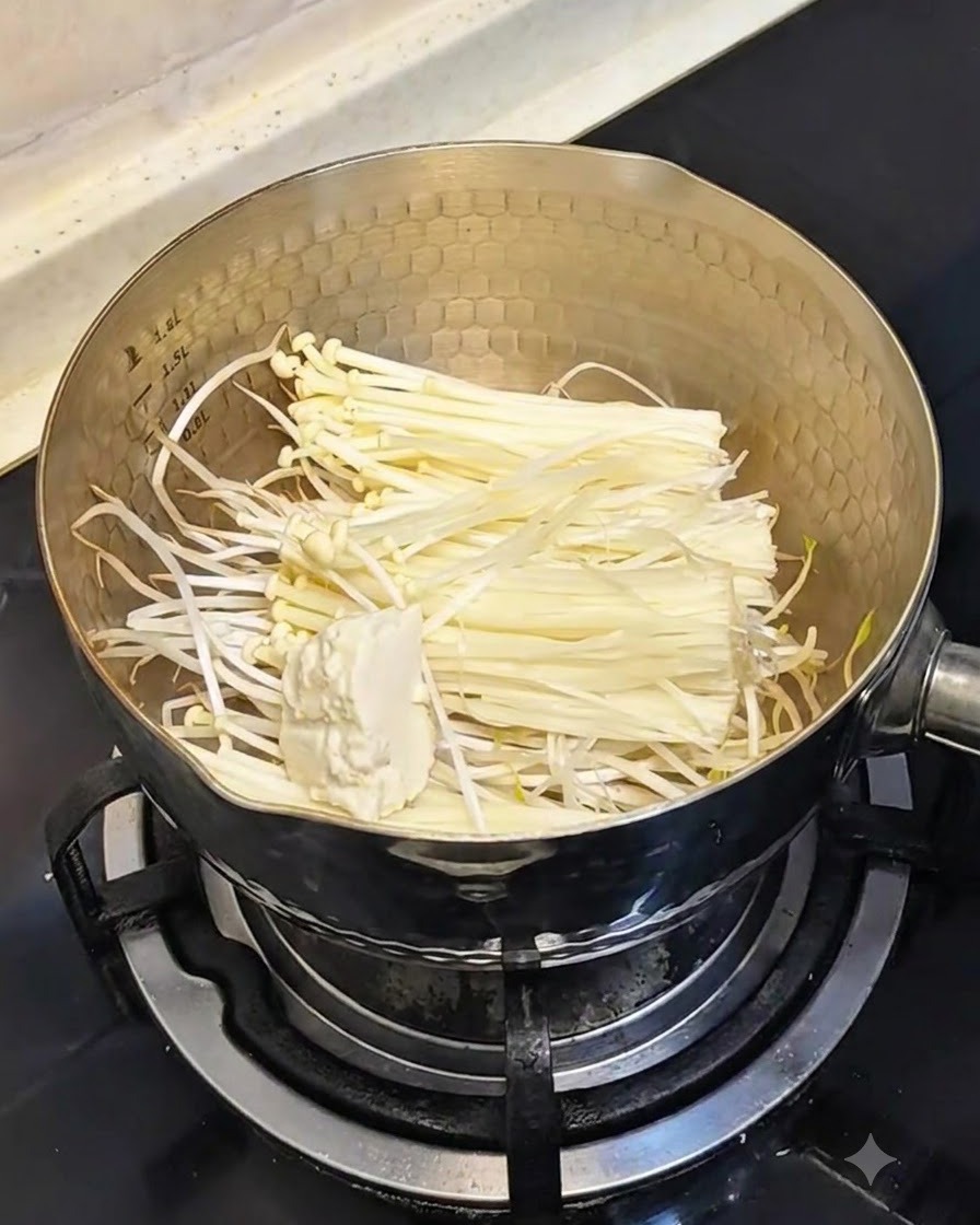 Ein Löffel mit weichem Seidentofu wird in den Topf mit Sprossen und Pilzen gegeben.