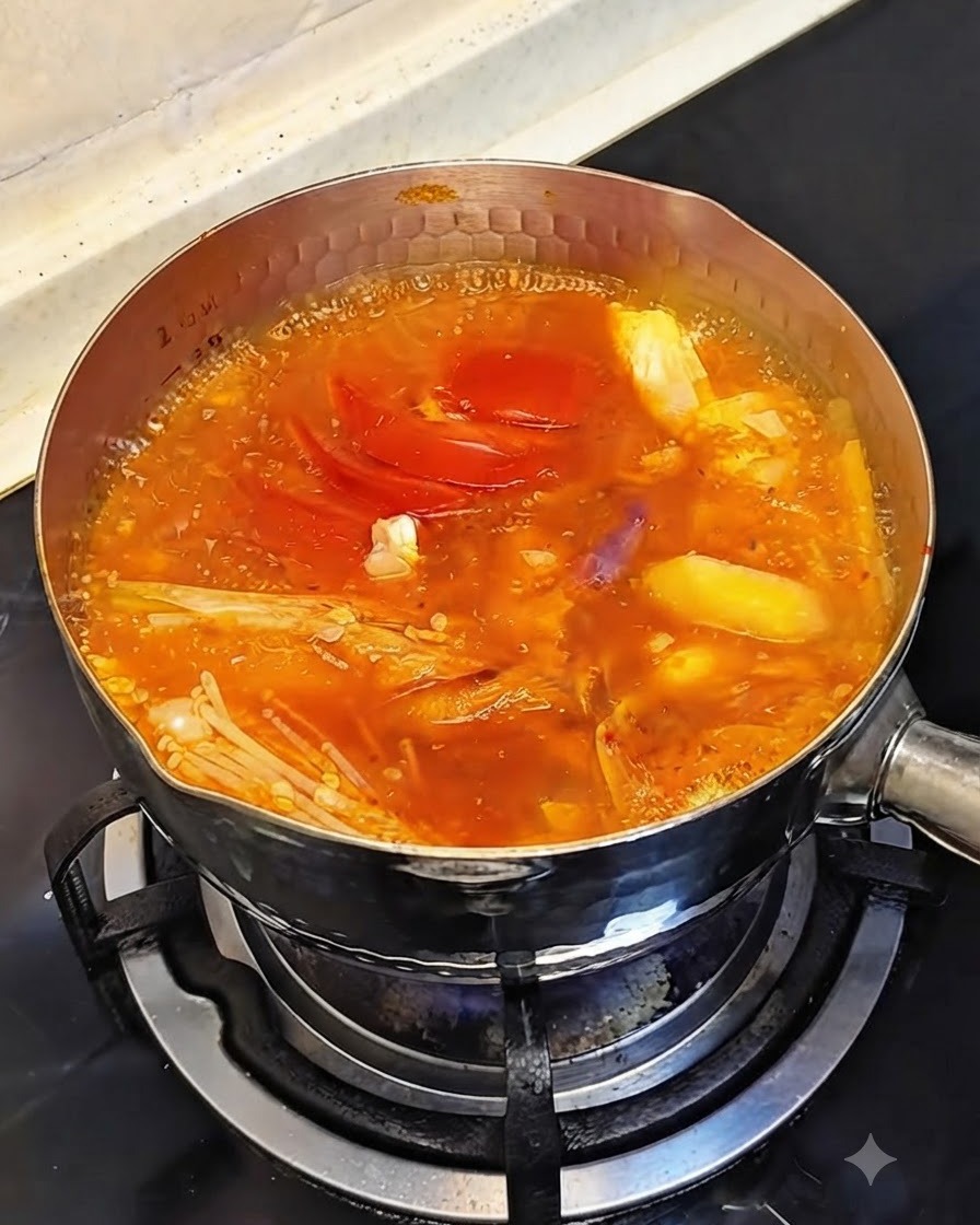 Ganze rohe Garnelen garen in dem blubbernden und köchelnden roten Eintopf.