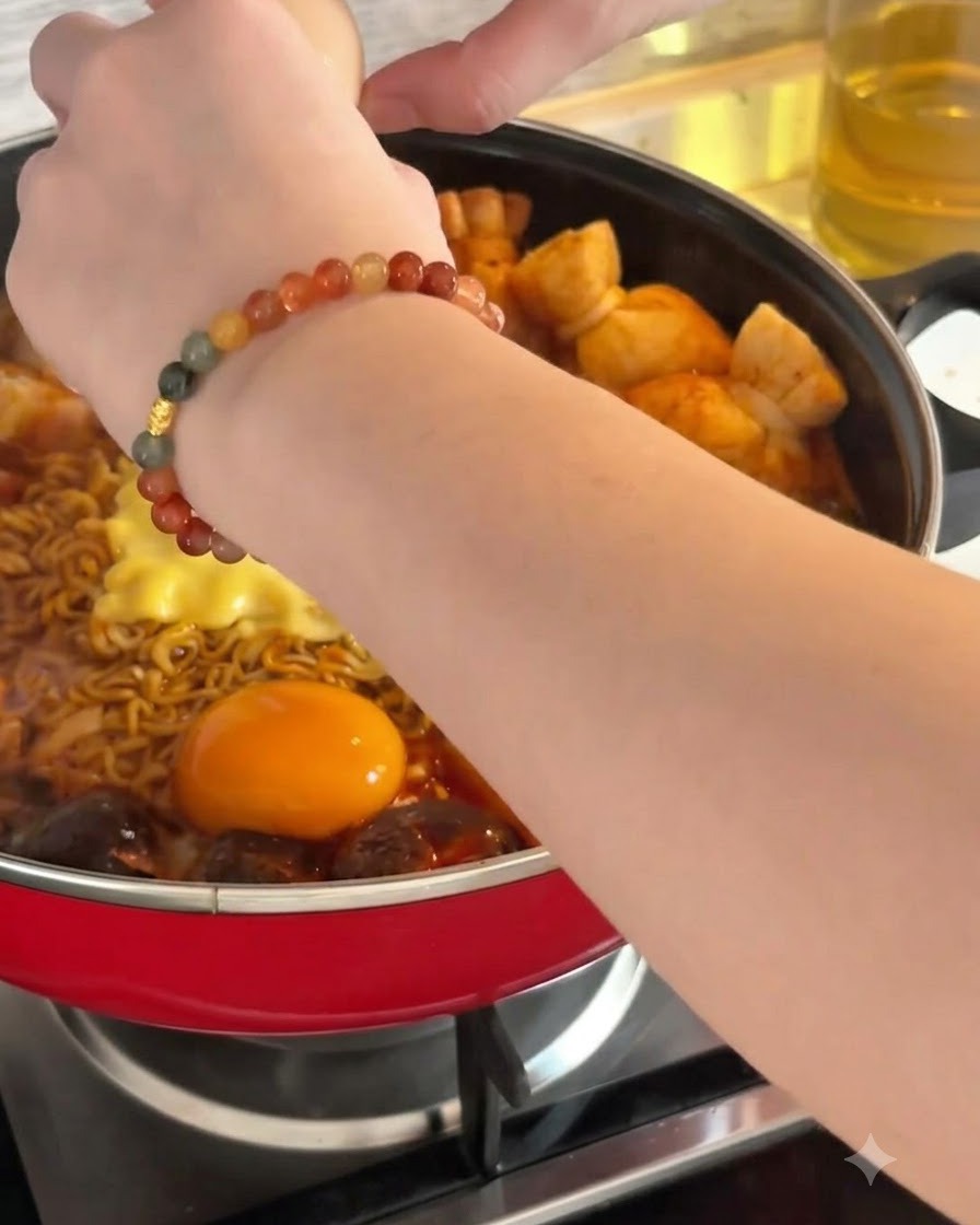 Ein rohes Ei wird neben Nudeln und Käse in die heiße Brühe geschlagen.