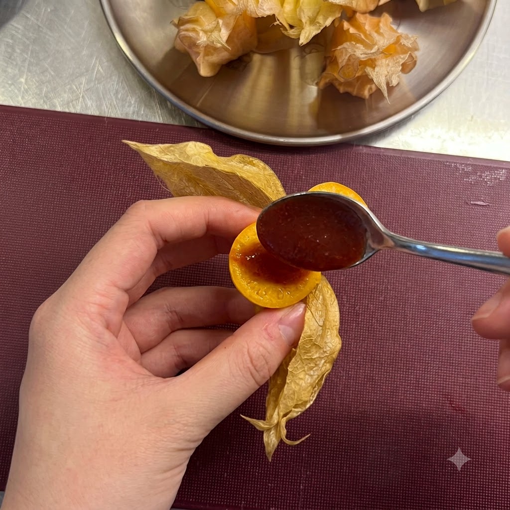 Ein kleiner Löffel füllt rote Chilisauce in die Mitte einer aufgeschnittenen Kapuzinerbeere.