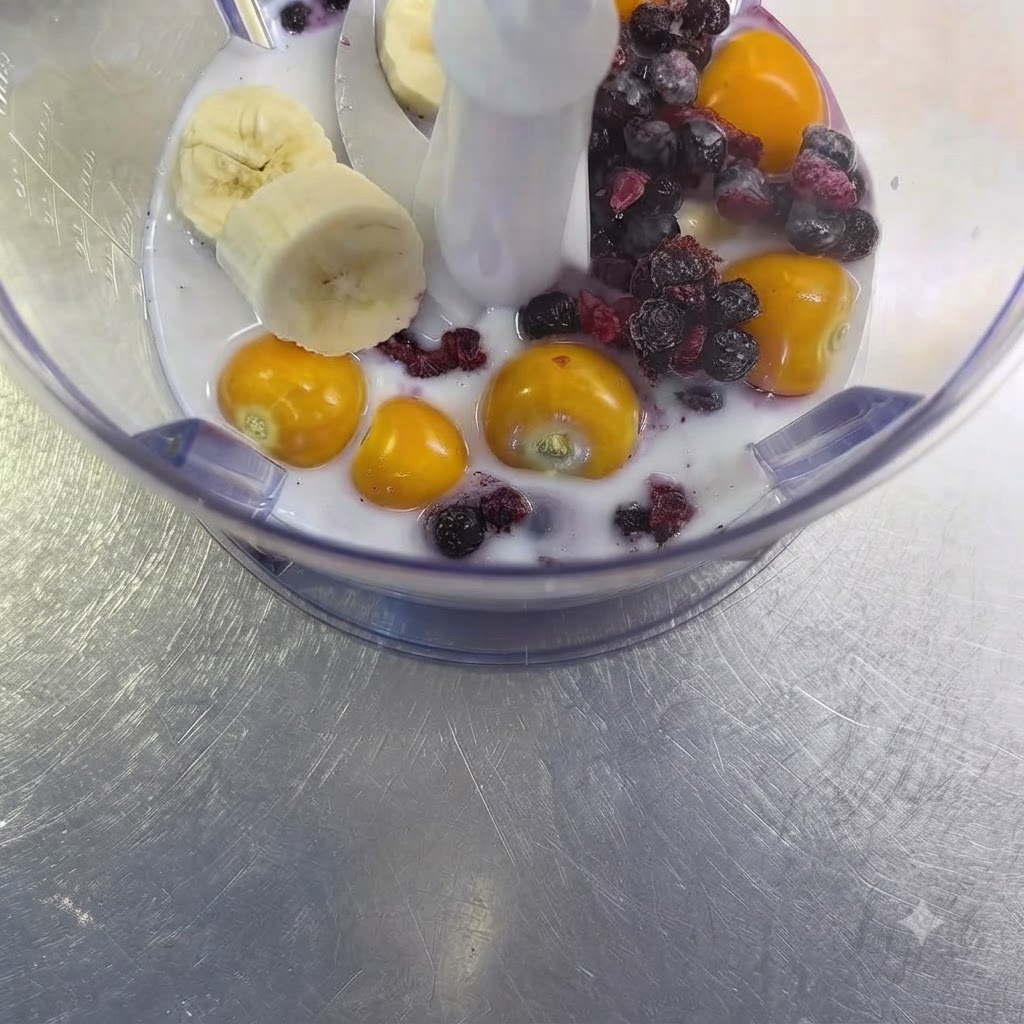 Eine rohe Knoblauchzehe liegt im Mixer zwischen Früchten und Milch.