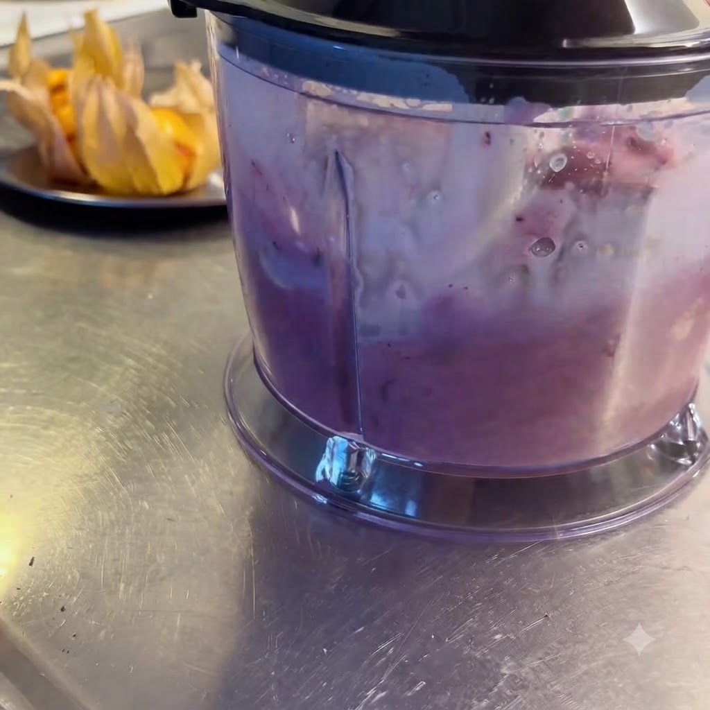 Ein Mixer verarbeitet die Zutaten zu einem lila Shake.