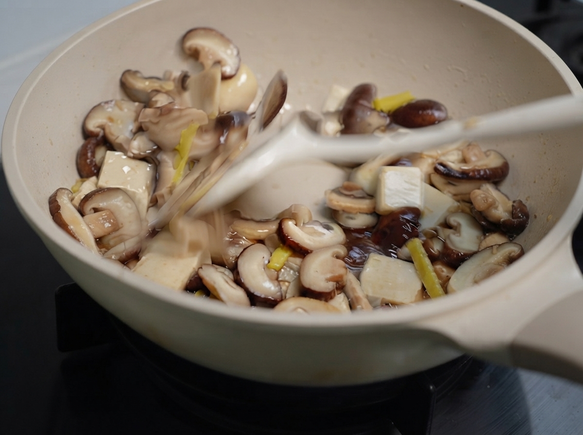 Gemischte Pilze und Ingwer werden mit einem Pfannenwender in einer Pfanne angebraten.