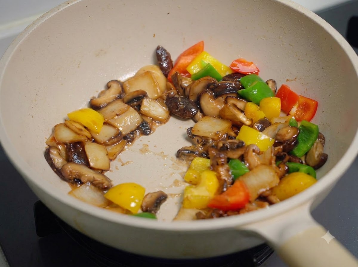 Pilze und Paprika werden in der Pfanne rasant geschwenkt und angebraten, gleichmäßig überzogen mit einer dicken dunklen Soße.