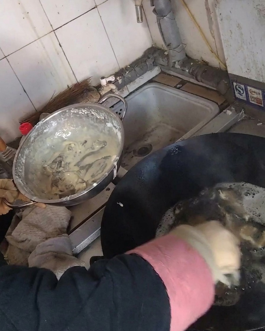 Frittieren von panierten Pilzstreifen in einem Wok mit heißem Öl.