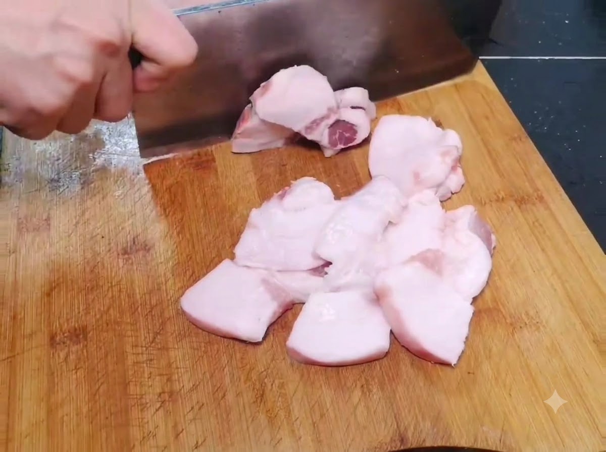 Dünne, breite Stücke rohen Schweinefleischs werden auf einem Holzschneidebrett in Scheiben geschnitten.