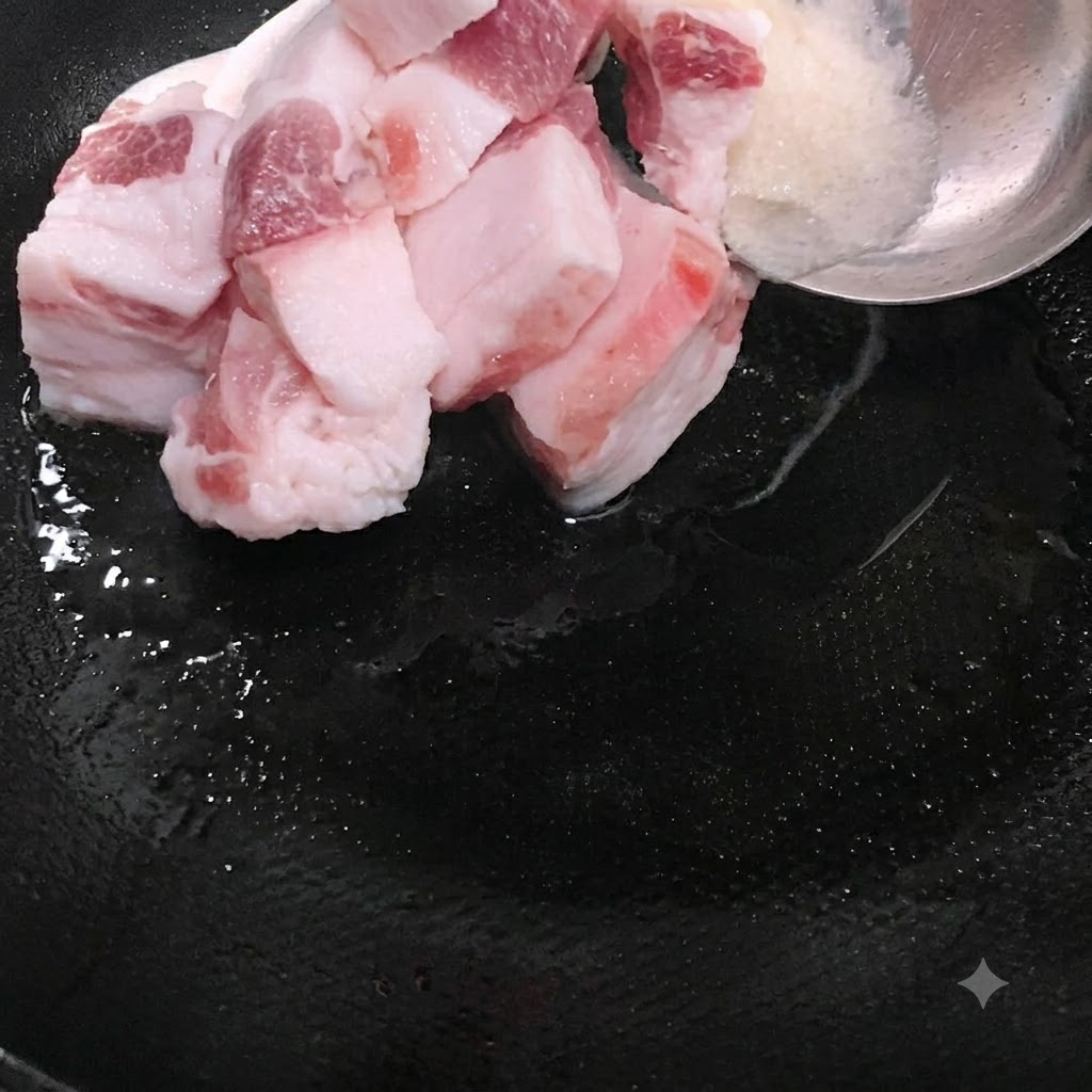 Fettige Schweinefleischscheiben werden zusammen mit geschmolzenem Schmalz in den Wok gegeben.