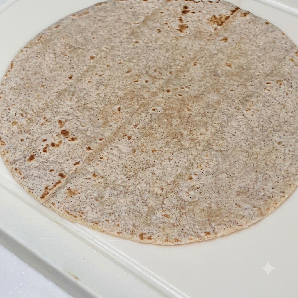 Eine Vollkuorn-Tortilla geschichtet mit Erdnussbuttersoße, Hähnchenstreifen, Rotkohl und frischem Salat.